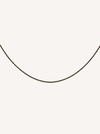 Gold tennis chain necklace featuring black cubic zirconia stones.