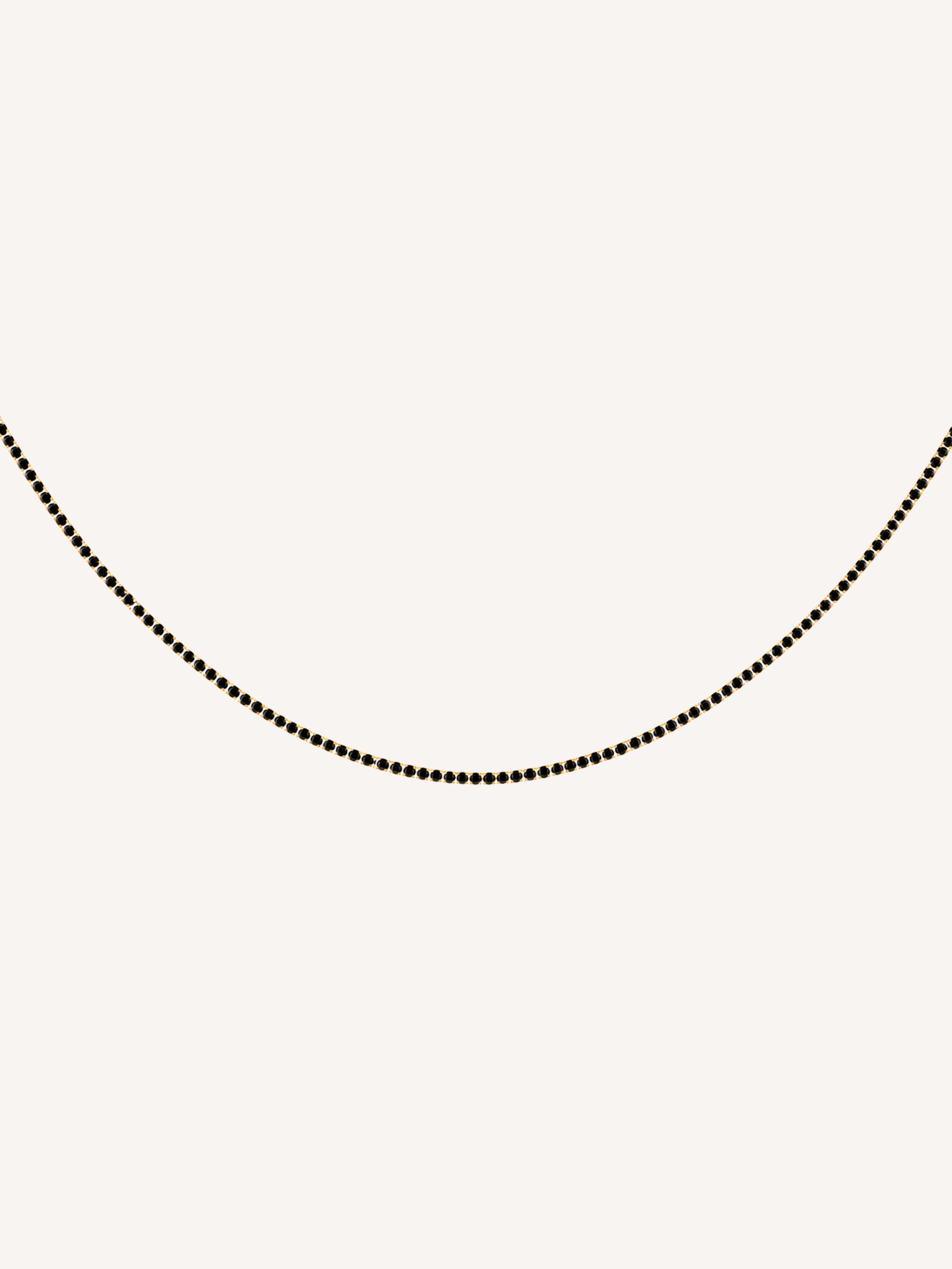 Gold tennis chain necklace featuring black cubic zirconia stones.