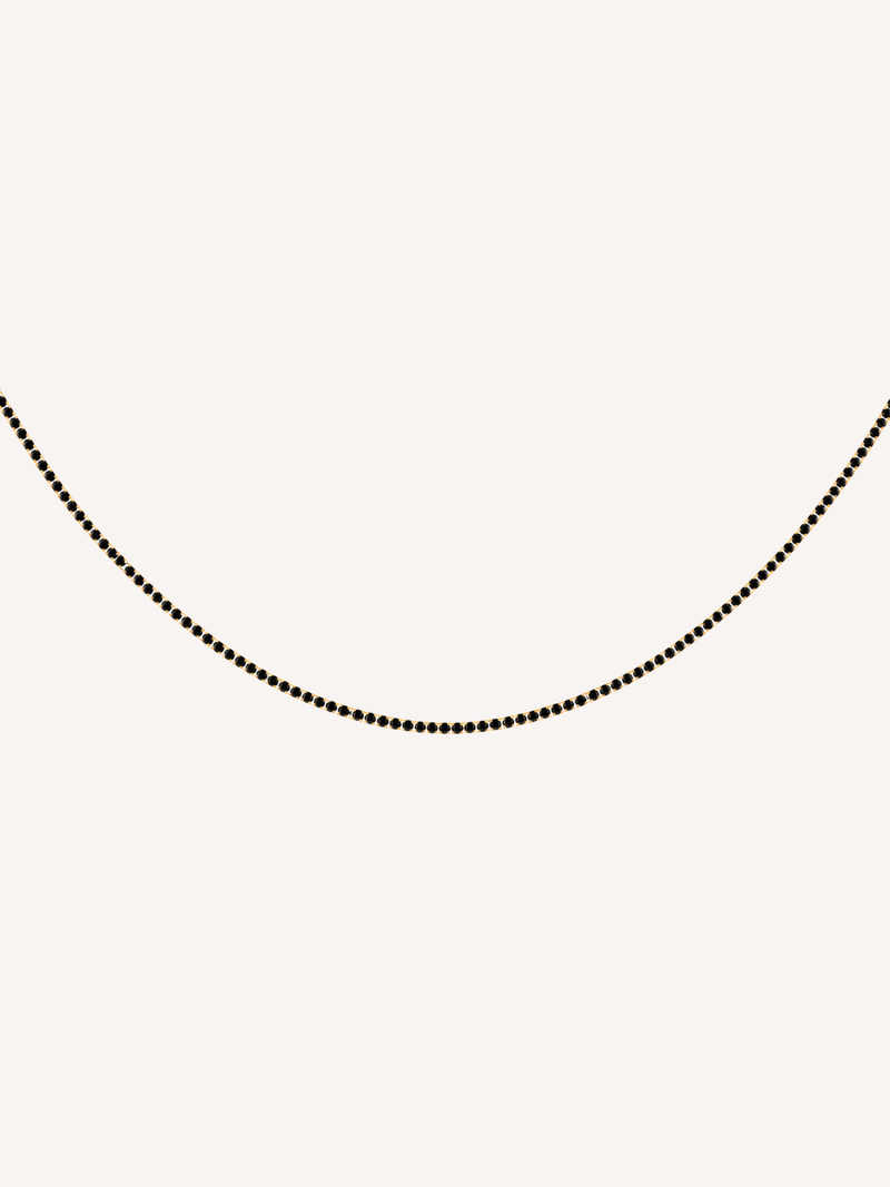 Gold tennis chain necklace featuring black cubic zirconia stones.