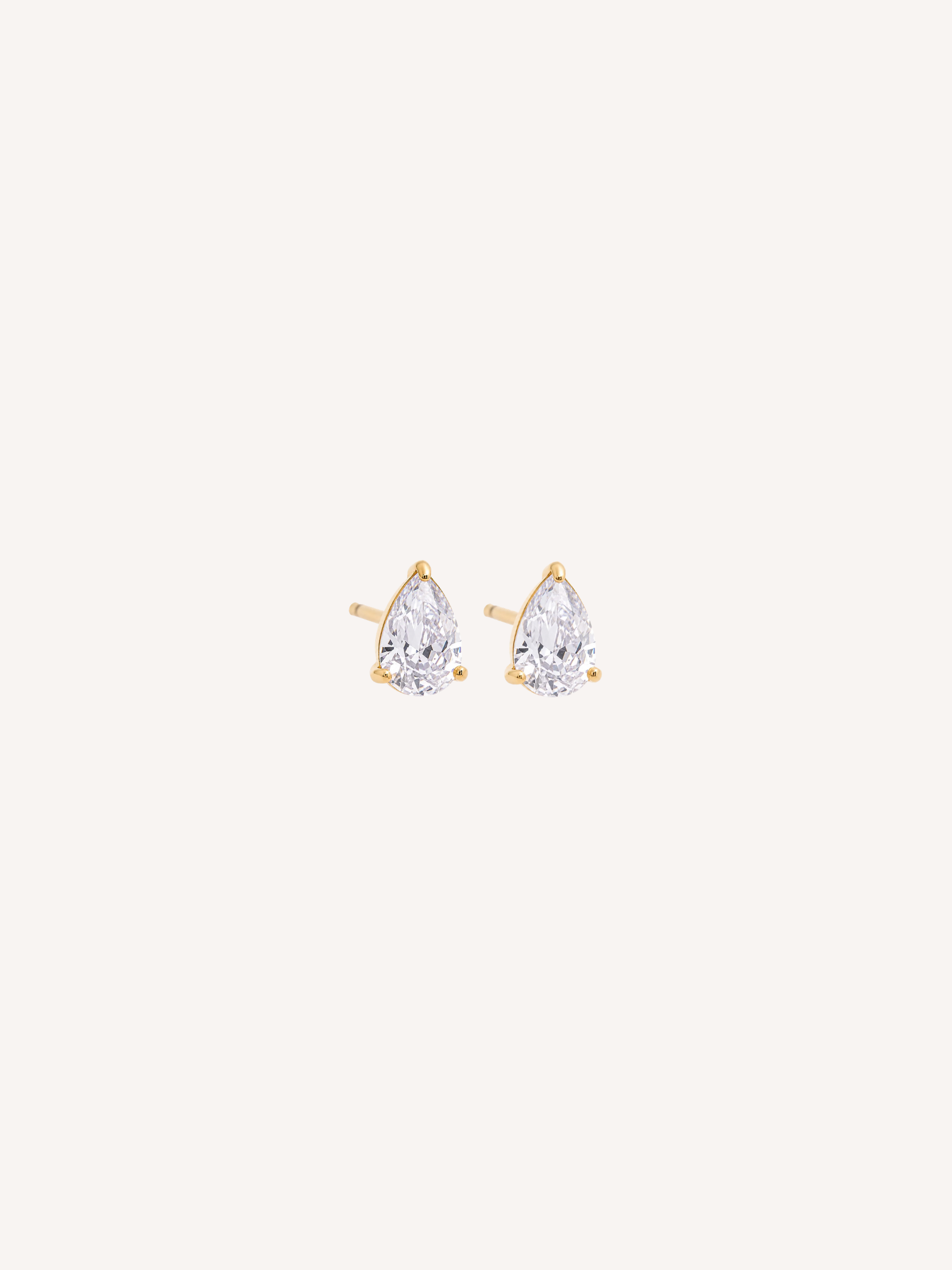 Tiny gold stud earrings with pear-cut cubic zirconia stones held by claw prongs.