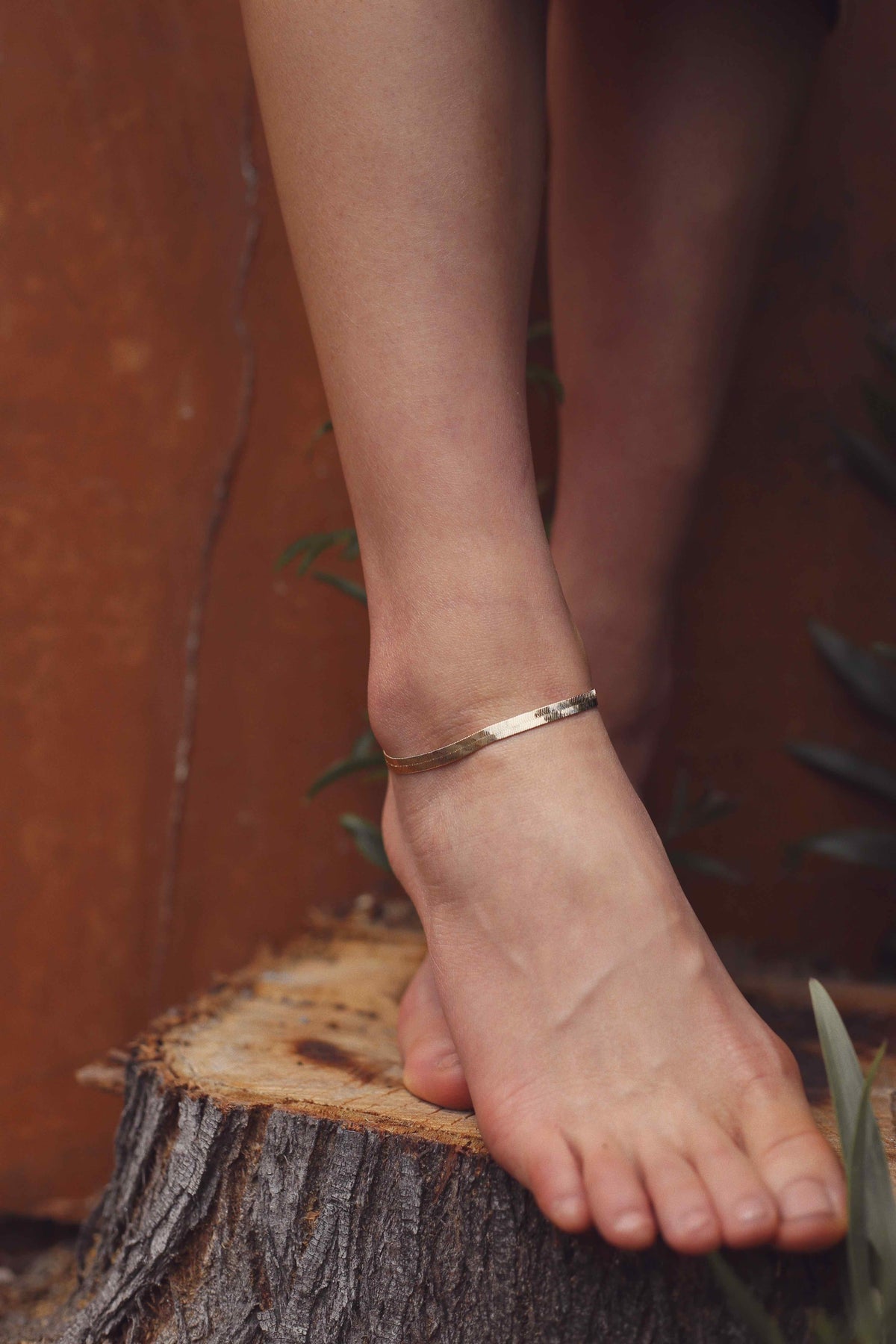 Gold flat herringbone snake chain anklet worn on ankle — classic gold anklet Ten Wilde